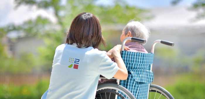 Pflegerin und Frau im Rollstuhl im Park